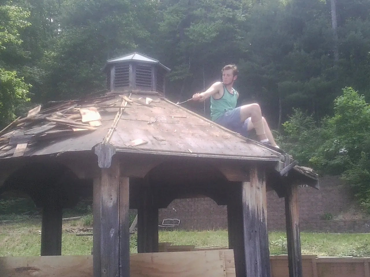 Tearing the old roof off a wooden gazebo before new shakes in Danville